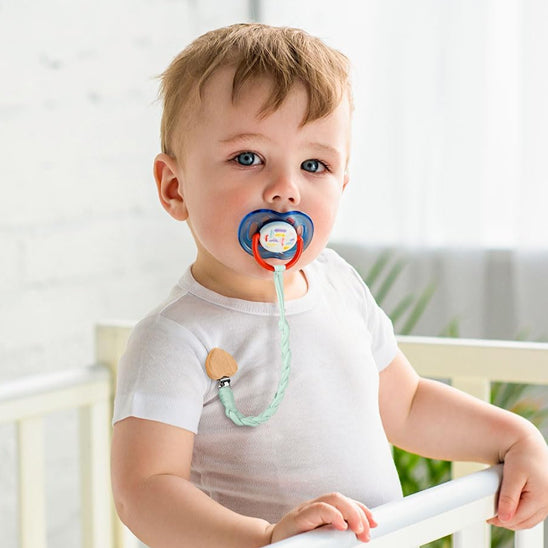 Attache-tetine verte en coton utilisée par un bébé.