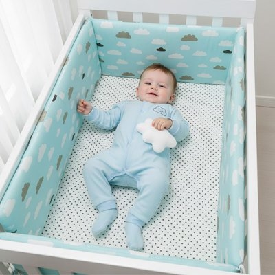 Bébé allongé dans un lit équipé d’un tour de lit bébé garçon bleu clair