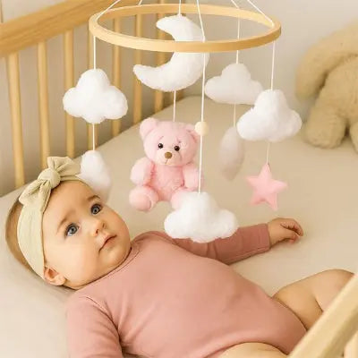 Bébé allongé sous un  mobile pour lit bebe apaisant rose et blanc doux