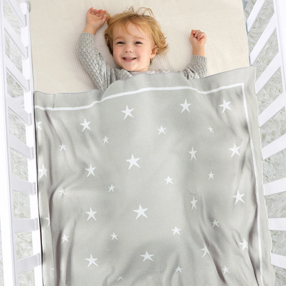 Bébé allongé sous une couverture étoile pour bébé en coton gris
