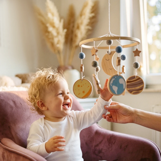 Bébé souriant touche un mobile etoile en bois motif espace 