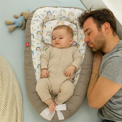 Bébé dort dans un réducteur de lit bébé Arc-en-ciel
