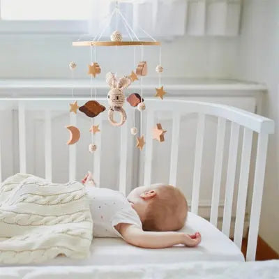 Bébé endormi dans un lit avec mobile bébé fabriqué à la main 