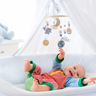 Bébé heureux dans son lit mobile bébé musical en bois suspendu