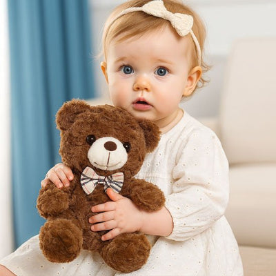 Bébé tenant un ours en peluche marron 
