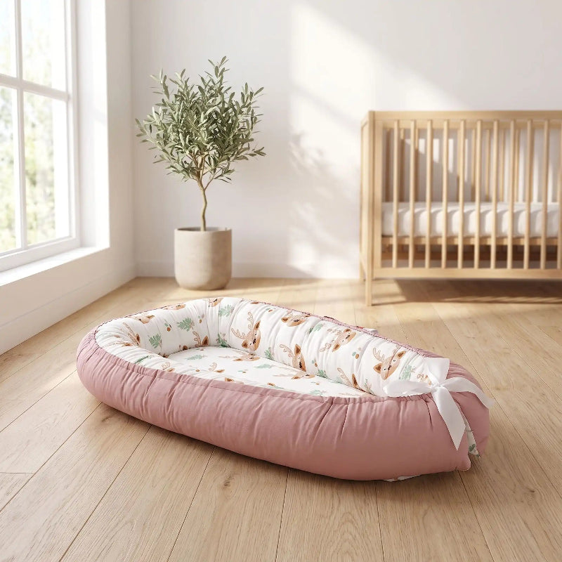 Cocon bébé rose à motif faons posé dans une chambre lumineuse