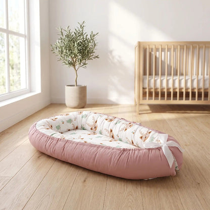 Cocon bébé rose à motif faons posé dans une chambre lumineuse