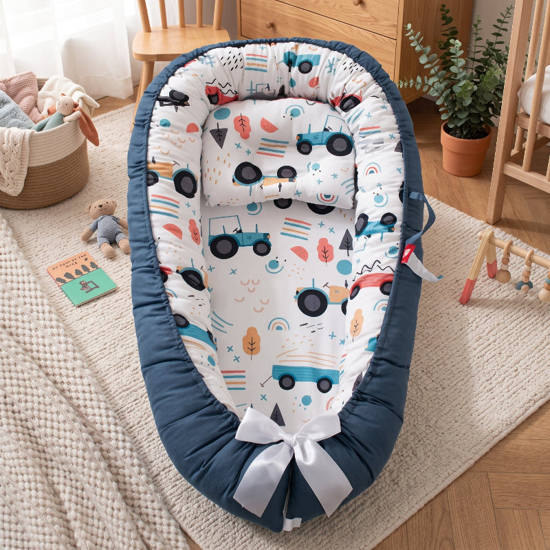 Cocon pour bébé à petites voitures posé au sol du salon