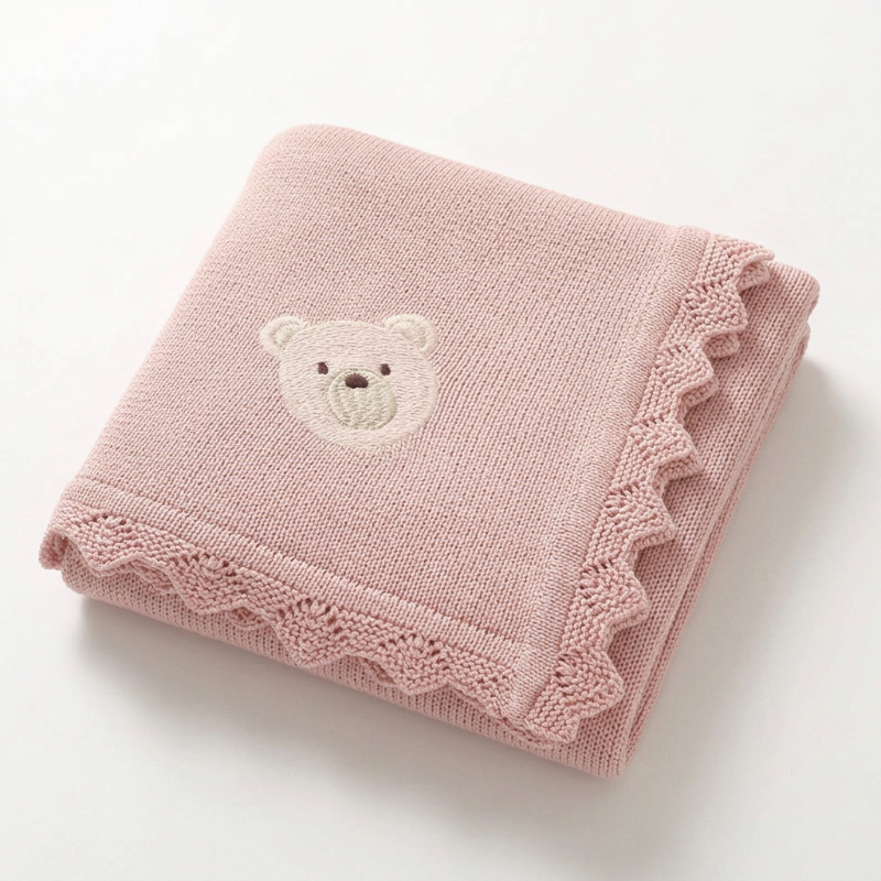 Couverture bébé au tricot rose poudré à ourson brodé
