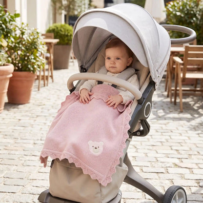 Couverture bébé au tricot rose poudré sur un bébé en poussette