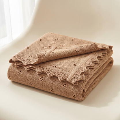 Couverture en tricot bébé camel pliée sur un fauteuil
