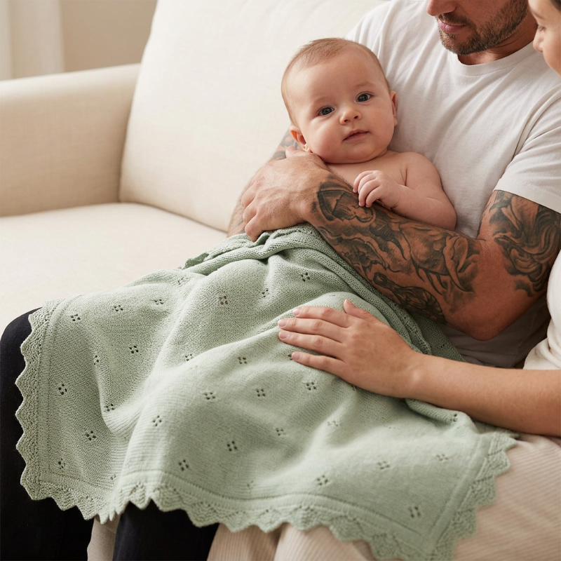 Couverture en tricot bébé vert sauge sur un bébé dans les bras de papa