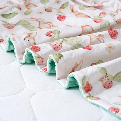 Couverture hiver bébé, gros plan sur l'imprimé fraises et le minky vert