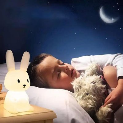 Enfant endormi avec un doudou près d’une veilleuse lapin 