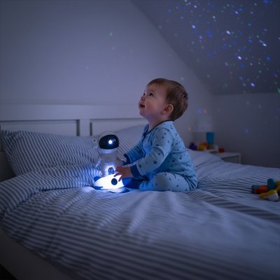 Enfant observant une veilleuse projecteur créant une spirale lumineuse au plafond.