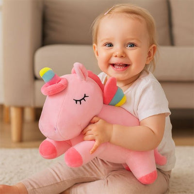 Enfant sourit en tenant une licorne en peluche rose