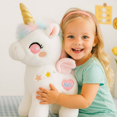 Fillette jouant avec une peluche licorne blanc rose