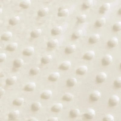 Gros plan sur le tissu minky doux à petits pois du tour de lit rembourré blanc cassé