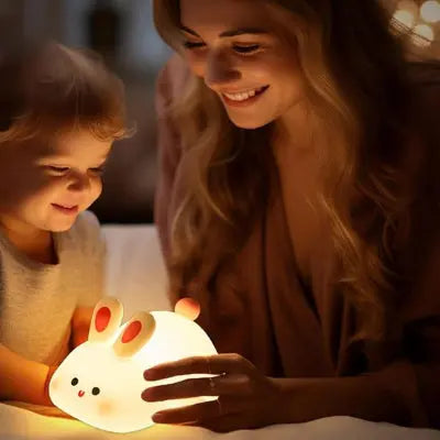 Mère et fils joyeux qui regarde une veilleuse bébé en silicone forme lapin


