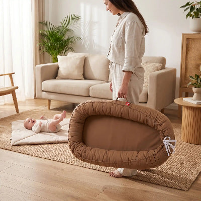 Parent transportant un réducteur de lit bébé portable avec un bébé
