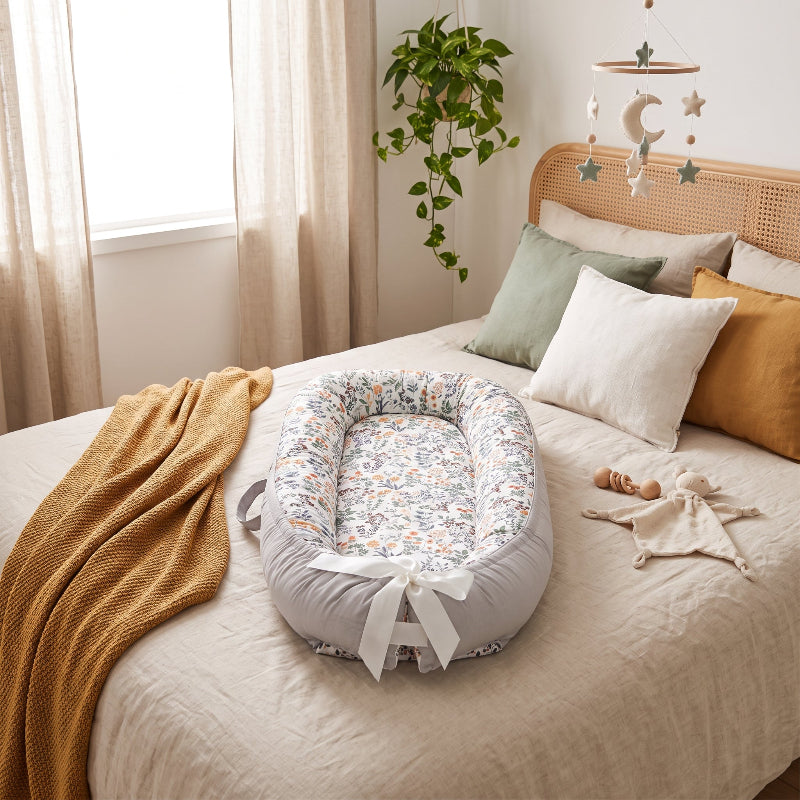Réducteur de lit bébé imprimé fleuri, vue de face avec nœud en ruban