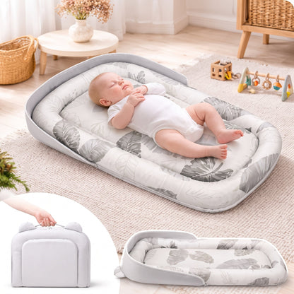 Réducteur de lit bébé pliable à feuilles grises posé au sol du salon