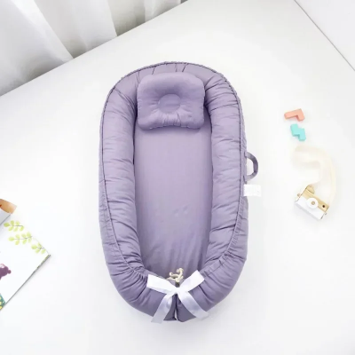 Réducteur de lit bébé mauve pastel anti-pression.