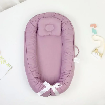 Réducteur de lit bébé rose poudré bionique.