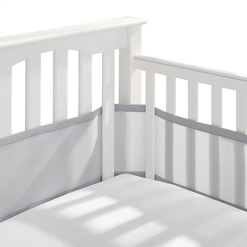 Tour de lit respirant gris autour des barreaux d’un lit bébé
