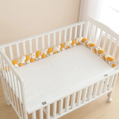 Tresse de lit bébé jaune et blanche apportant protection et confort dans un lit bébé