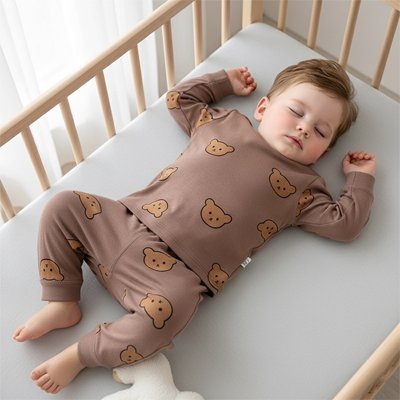 Bébé allongé portant un pyjama bébé garçon marron motifs.