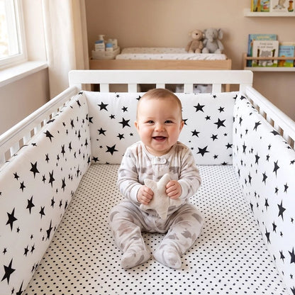 Bébé au centre d'un lit avec un tour de lit intégral 200x30 cm imprimé étoiles noires et blanches.