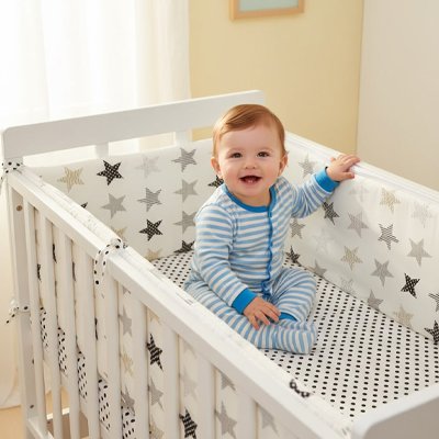 Bébé souriant dans son lit protégé par un tour de lit bébé rembourré