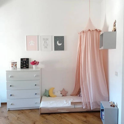 ciel de lit enfant rose au-dessus d'un lit bas