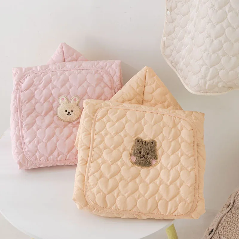 couverture de portage rose et beige posées à plat