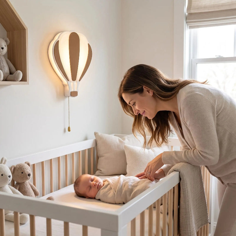 lampe montgolfière au mur, maman près du lit de bébé