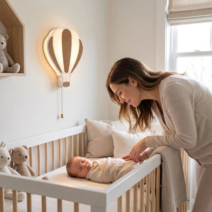 lampe montgolfière au mur, maman près du lit de bébé