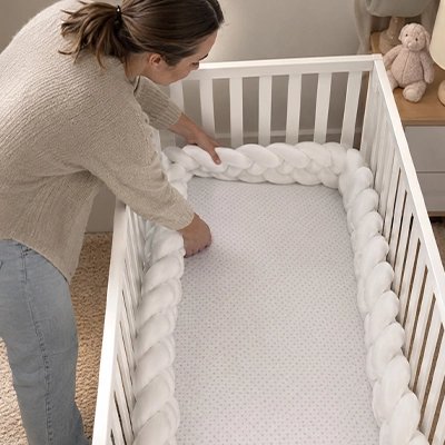 Maman installant un tour de lit tressé blanc