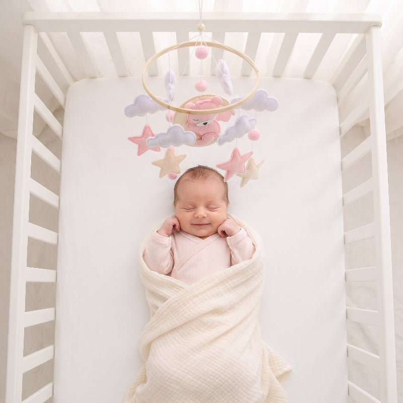 Mobile lit bébé fille en feutre rose au-dessus d’un berceau blanc