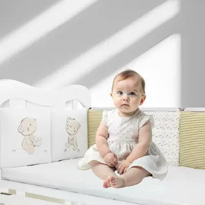 tour de lit modulable beige ourson dans un lit à barreaux
